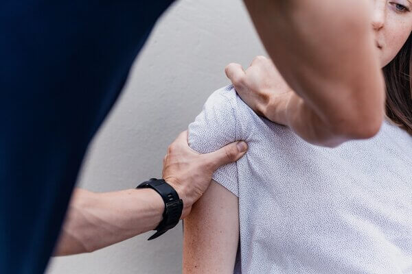 A physiotherapist works on a woman's shoulder