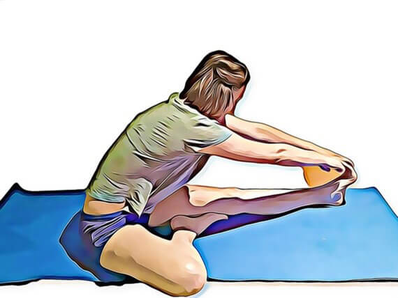 A person sits on a yoga mat, stretching a leg